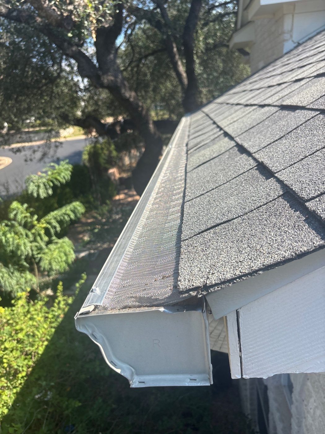 After: the same gutter covered with a fine-mesh stainless steel gutter screen.