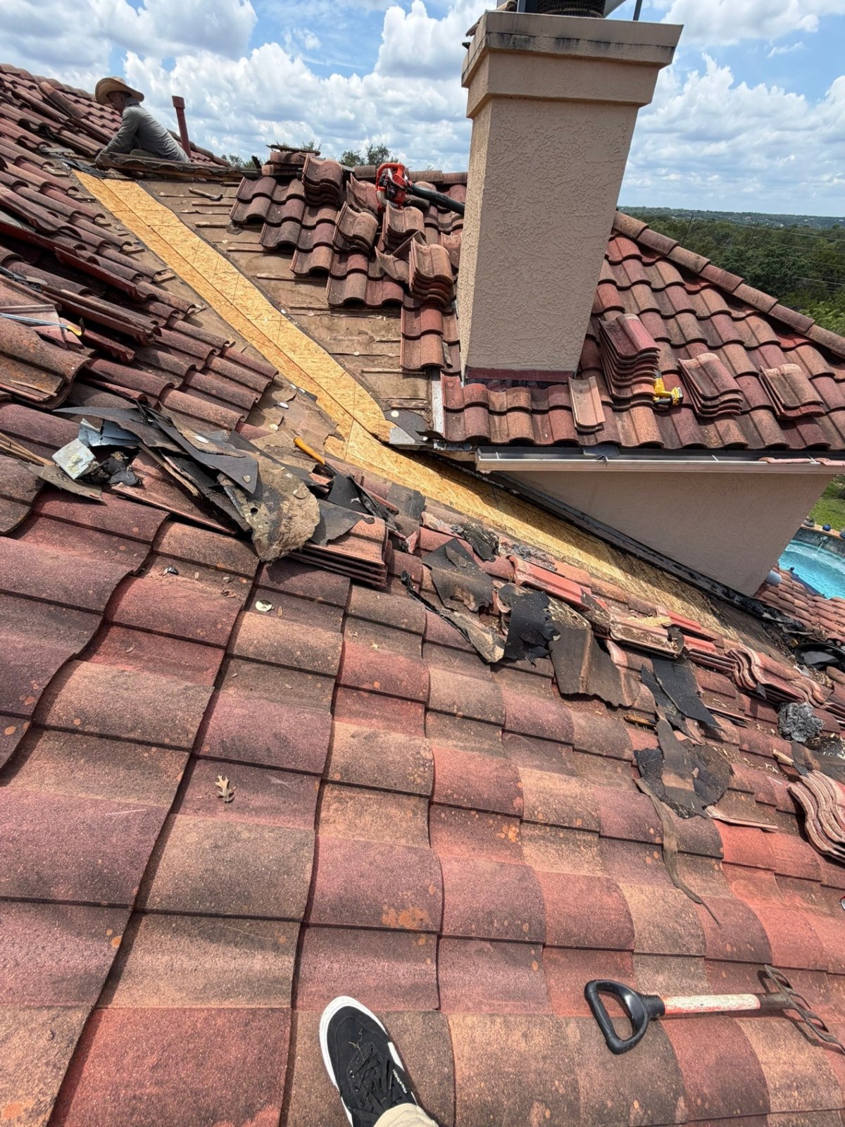 Tiles set aside and old underlayment removed, with rotten decking being replaced along the valley next to a stucco wall.