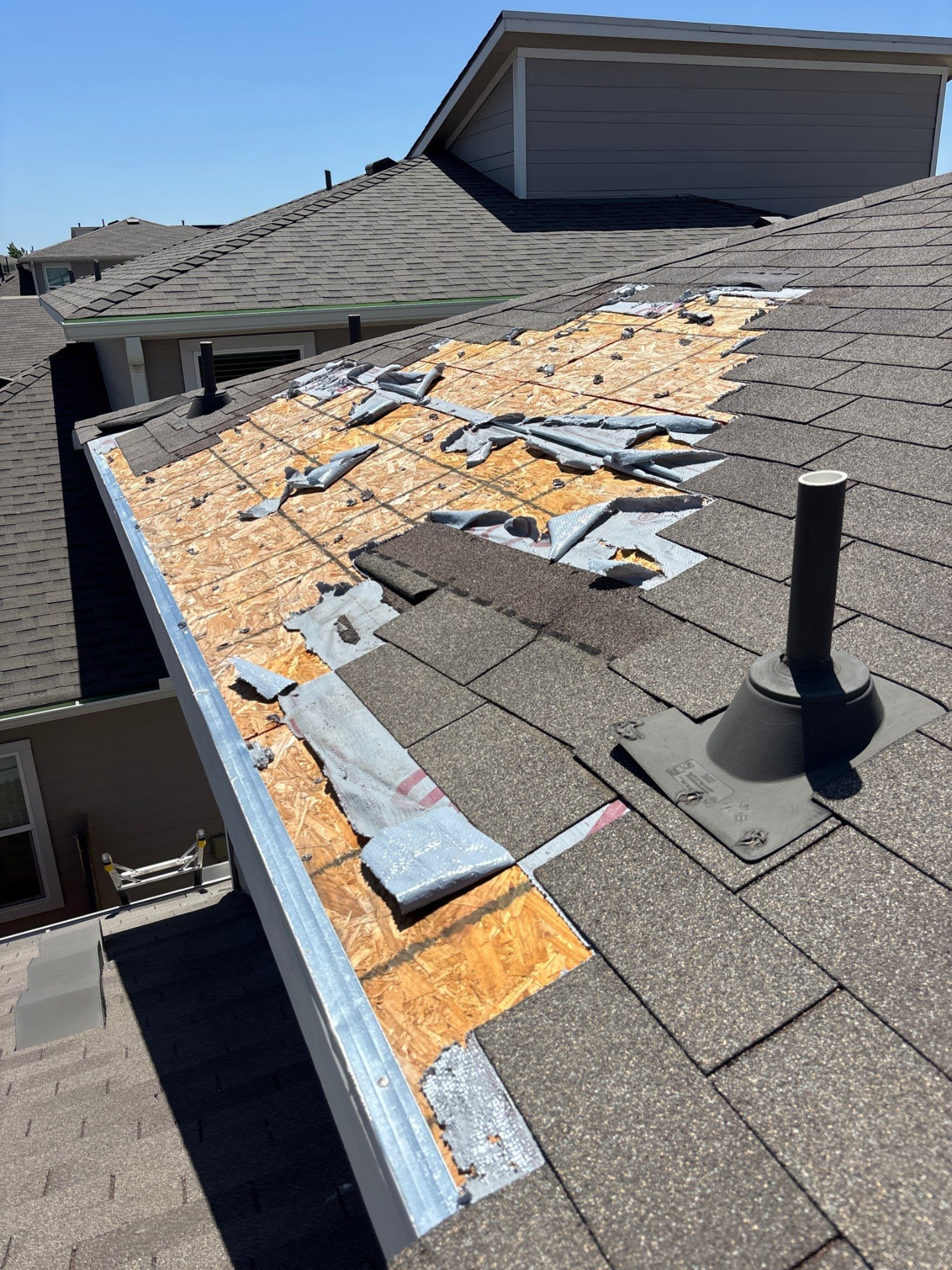 Asphalt shingle roof with a large area of exposed roof decking