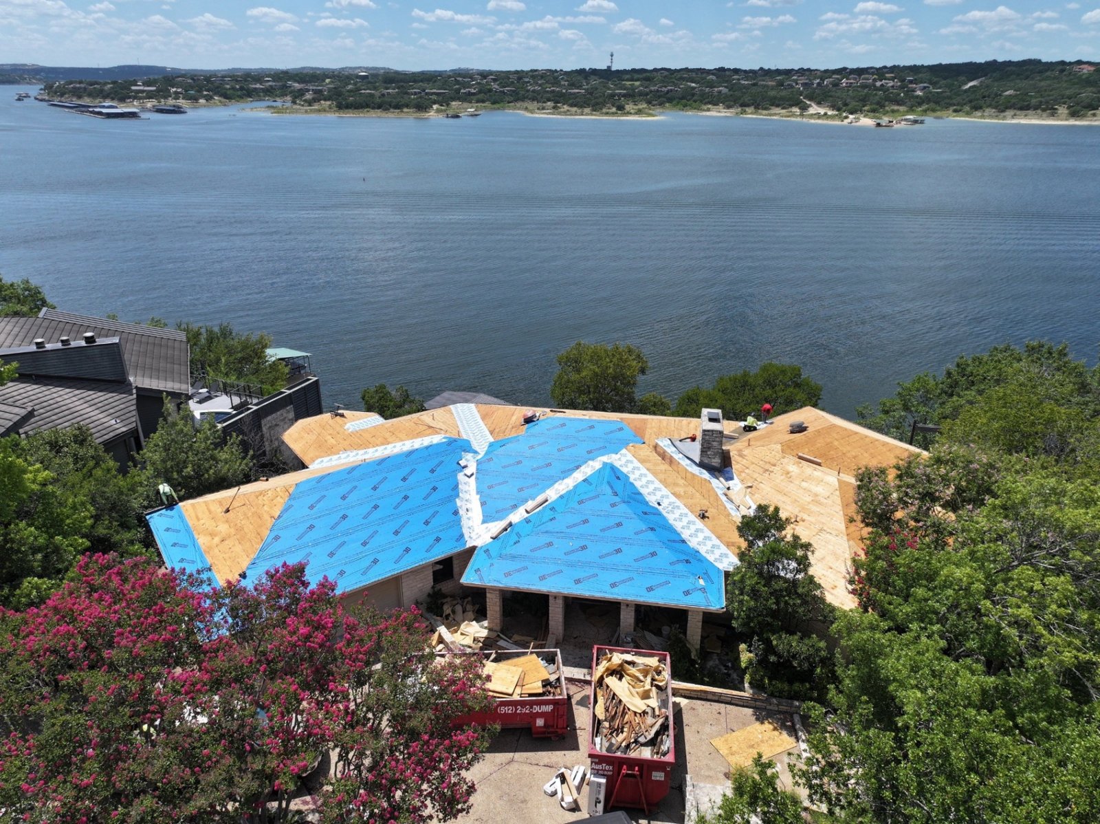 The roof deck partly covered in new underlayment, with Lake Travis behind the house.