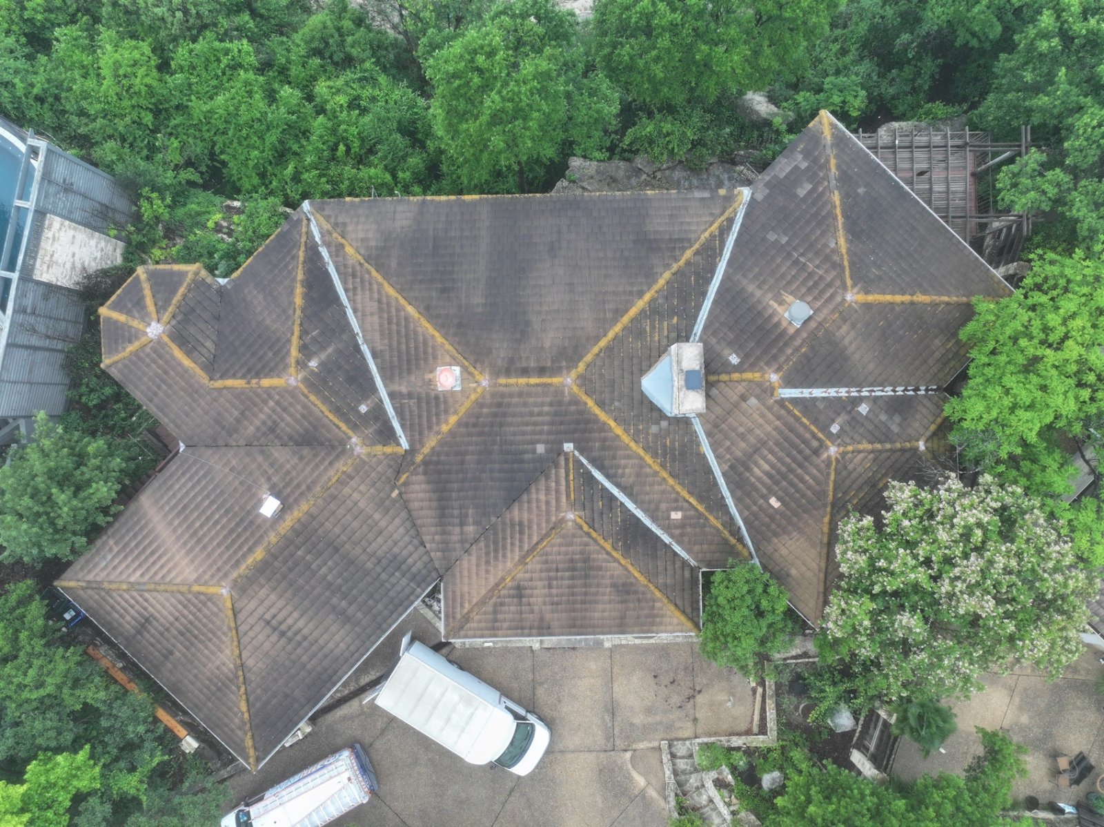 Overhead view of the aging concrete tile roof, with lichen growing along the hips and ridges.