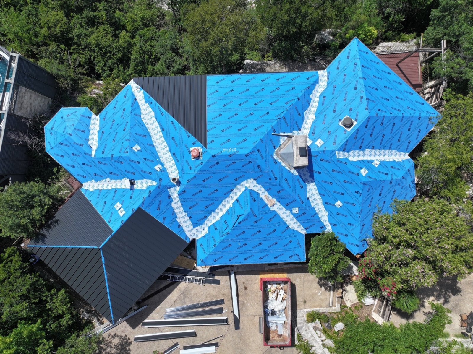 Matte black standing seam panels being installed over the new underlayment.