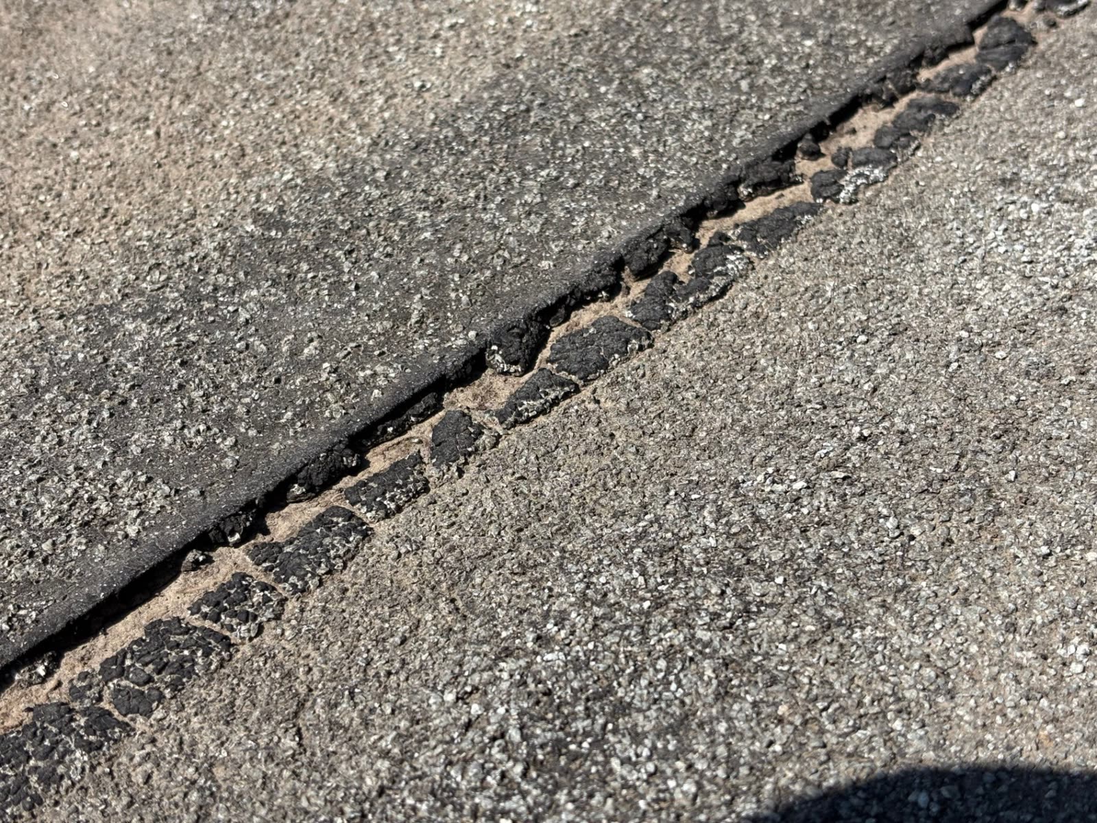 Close-up of a ModBit seam where the sealing tar has cracked into chunks and the overlap has pulled apart.