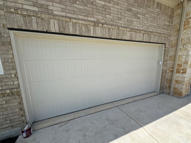 Completed white garage door after hail-damaged panel replacement and painting